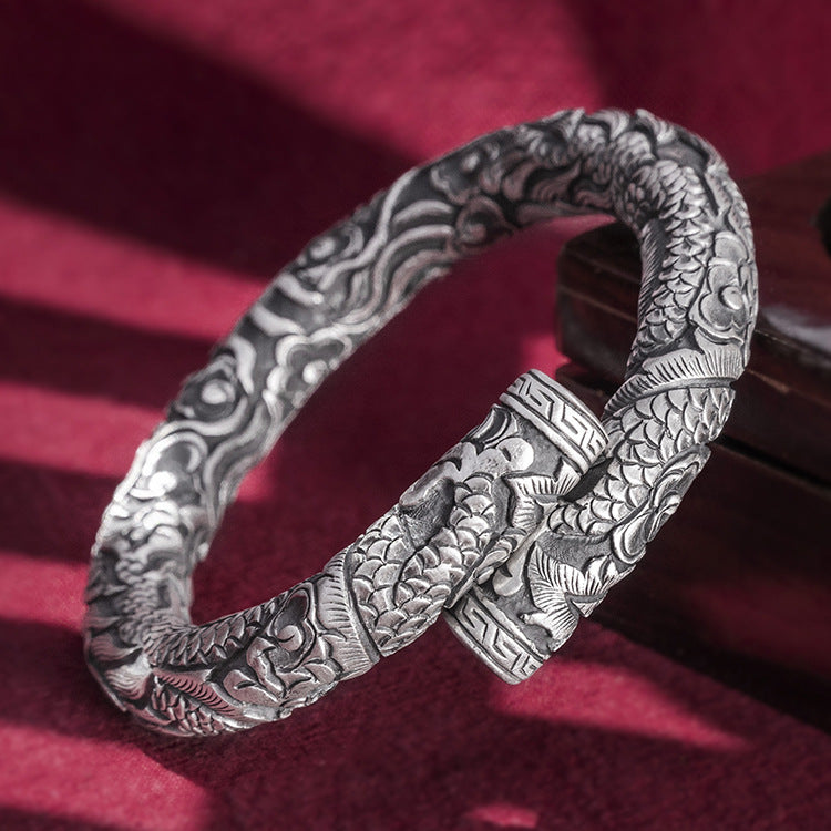 Silver bracelet with intricate designs on a red background