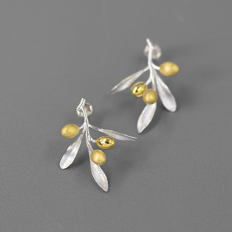 Silver and gold leaf earrings on a gray background