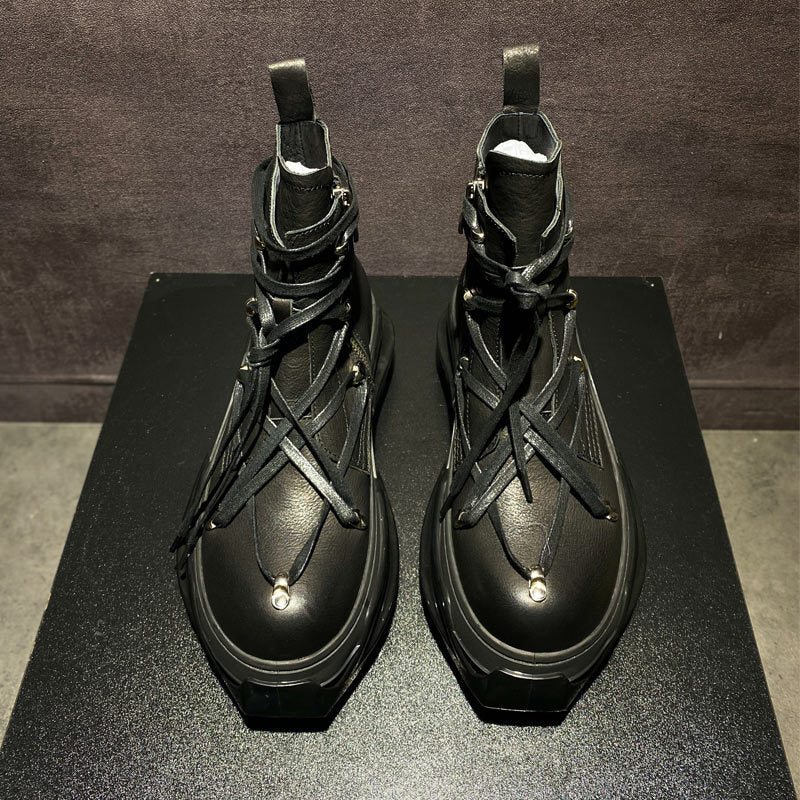 Pair of black high-top boots with unique design on a dark surface.