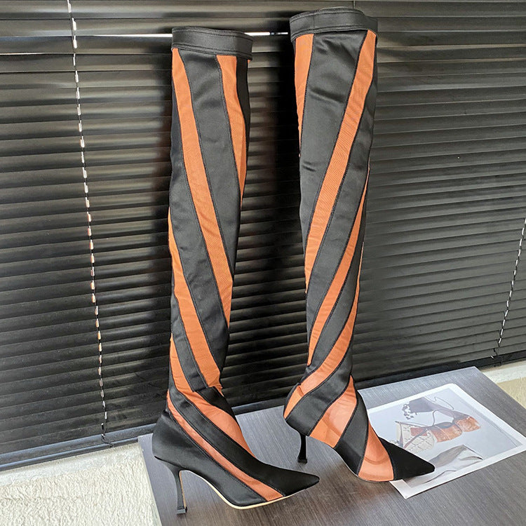 Black and orange striped knee-high boots on a surface with a blurred background