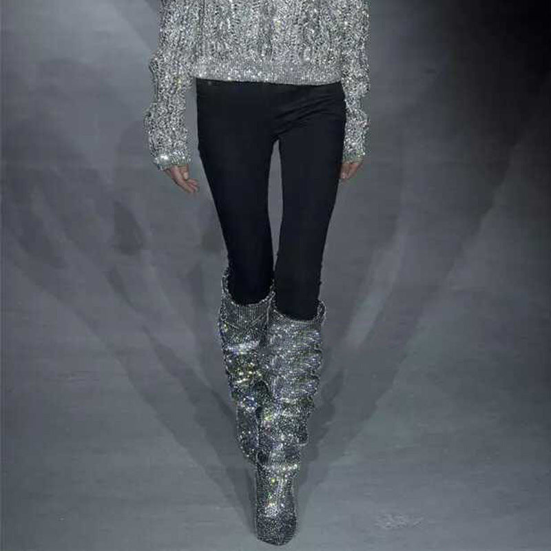 Person wearing silver sequin boots and a matching top on a gray background