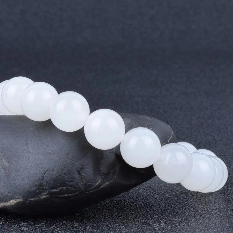 White beaded bracelet on a dark stone surface