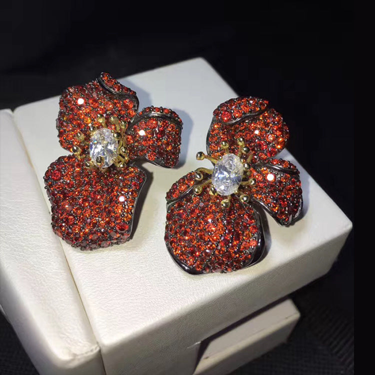 Pair of red gemstone earrings on a white stand with a dark background
