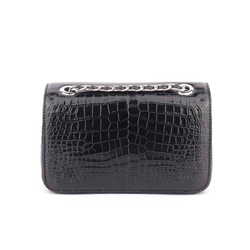 Black crocodile-patterned clutch bag with silver embellishments on a white background