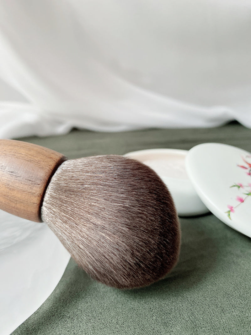 Makeup brush with wooden handle on a green surface
