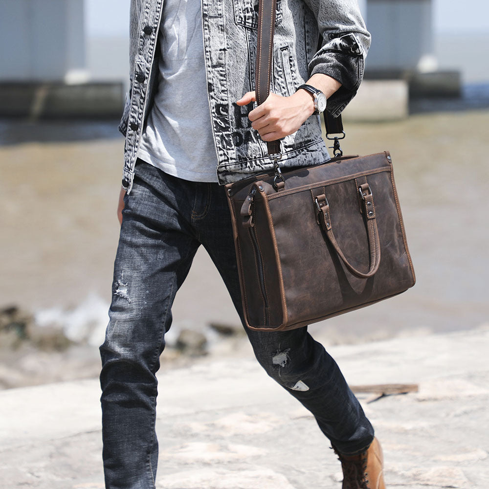 Person holding a brown leather briefcase in an urban setting
