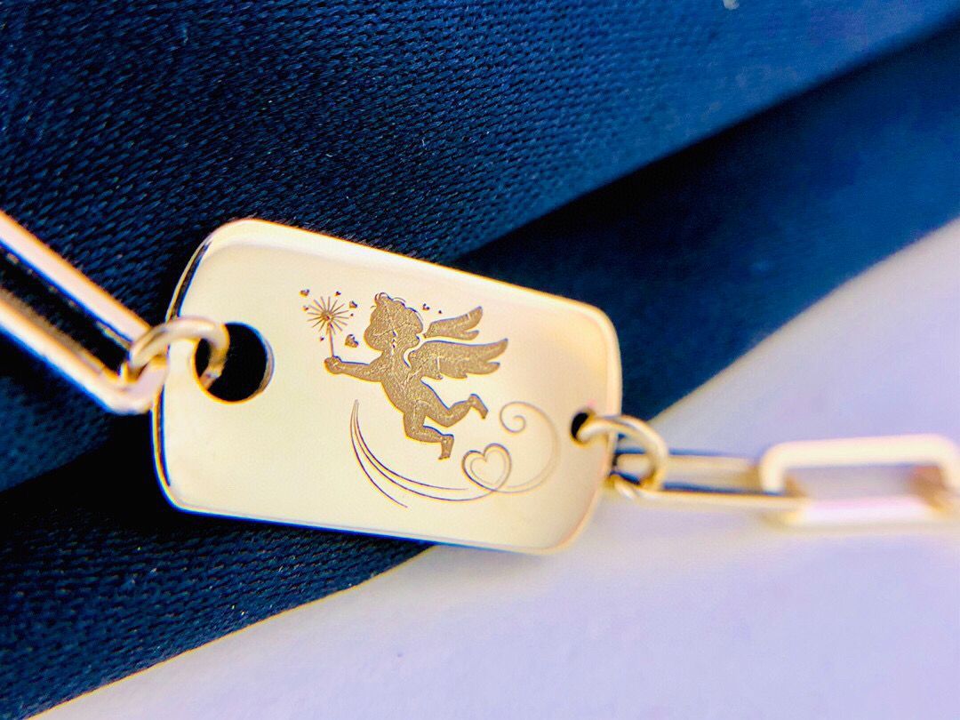 Gold keychain with angel design on a blue and white background