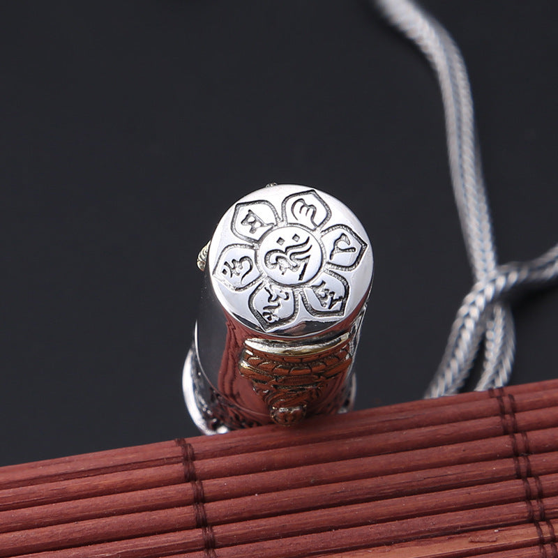 Silver pendant with intricate design on a dark background