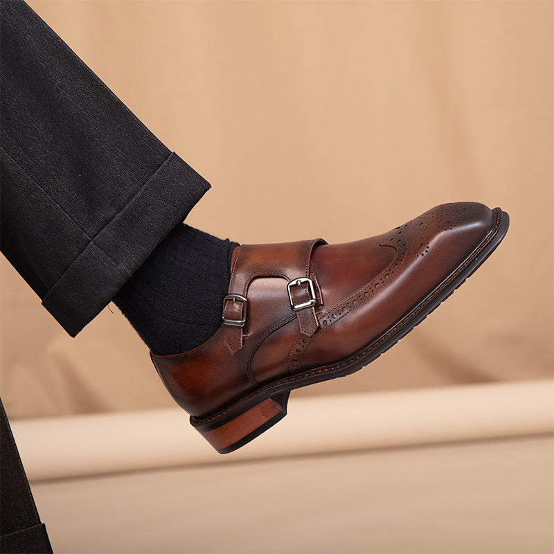 Brown leather monk strap shoe worn with black pants on a beige background