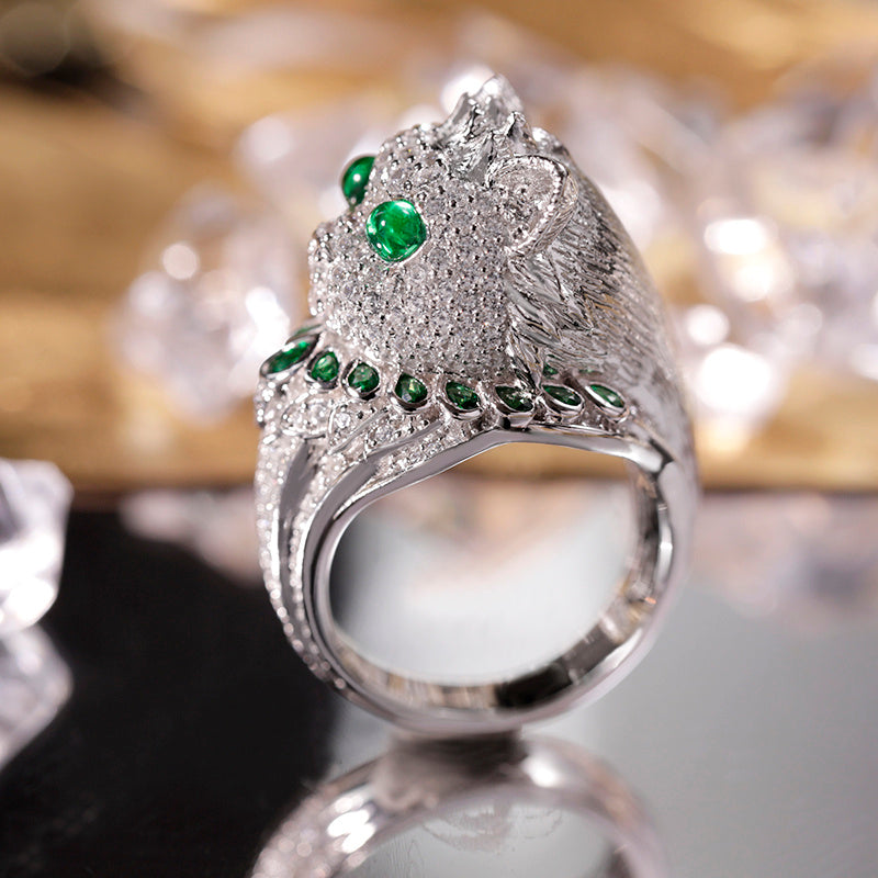 Silver ring with green gemstones on a reflective surface