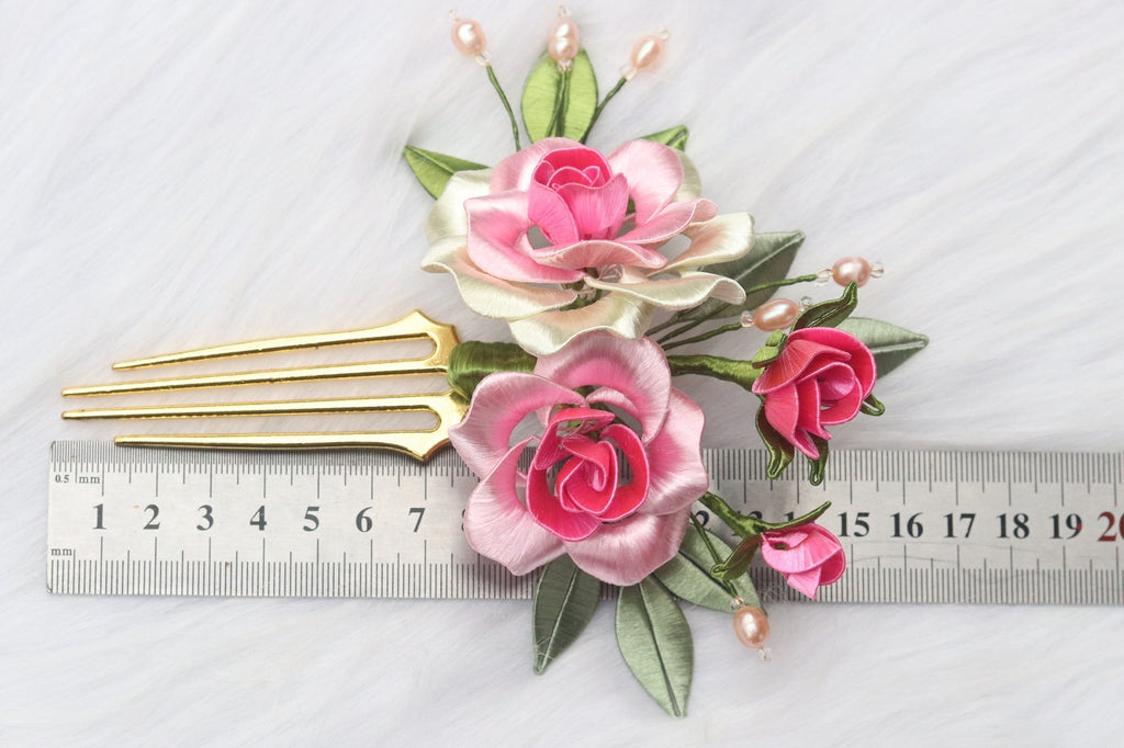 Decorative hair comb with pink and white flowers and green leaves, shown next to a ruler for scale.