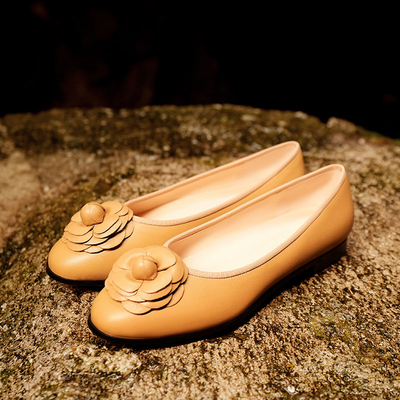 Pair of tan shoes with floral designs on a textured surface