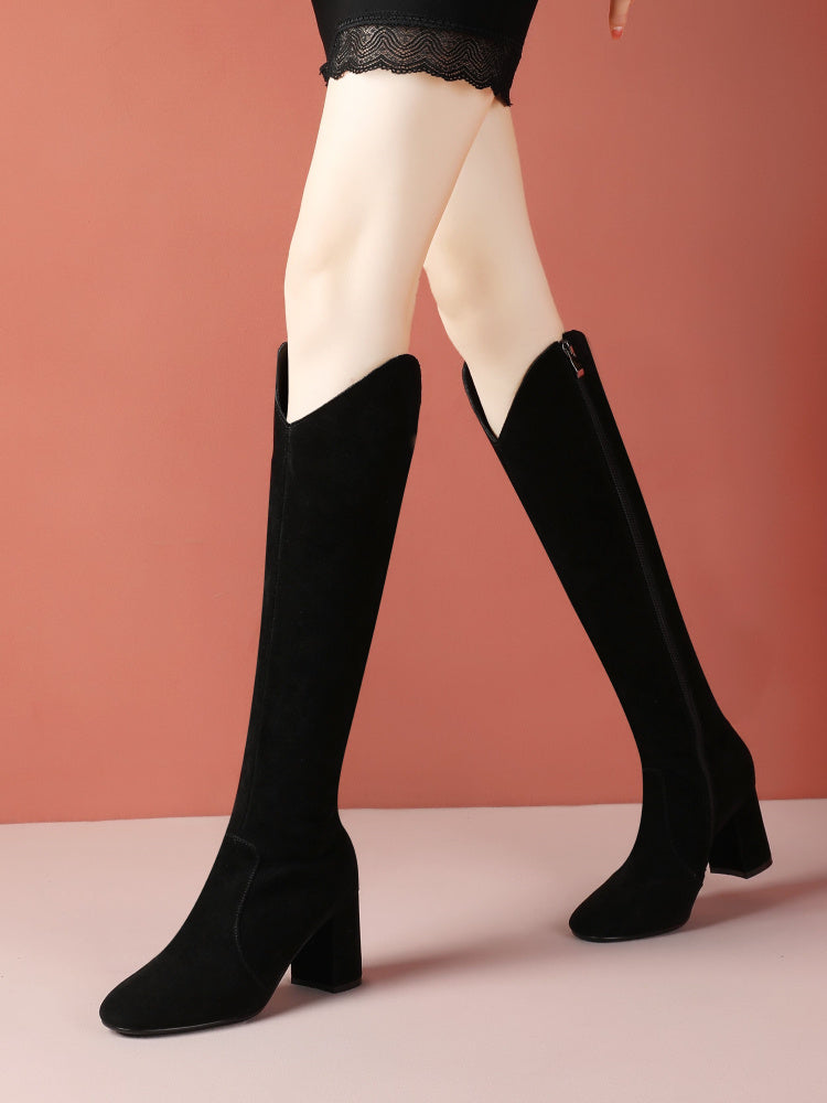 Black knee-high boots worn with white tights against a pink background