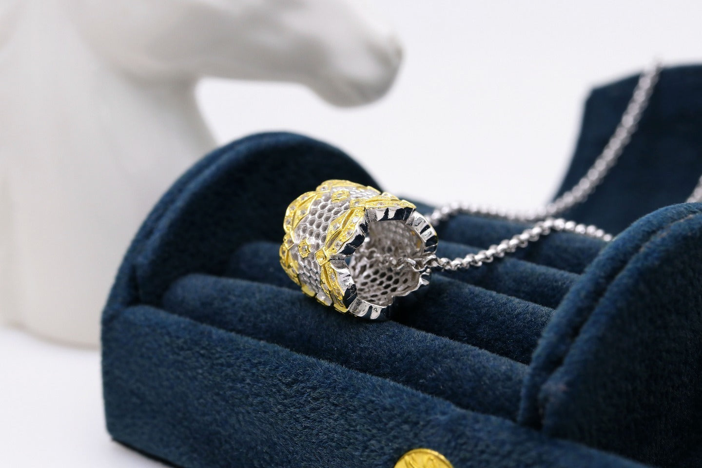 Silver and gold ring on a blue cushion with a blurred background