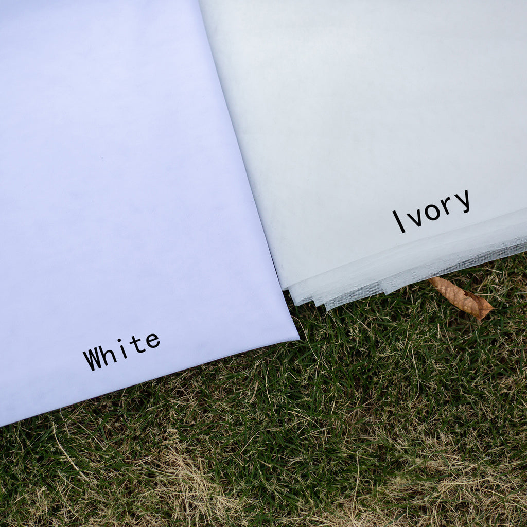 Two sheets of paper labeled 'White' and 'Ivory' on grass