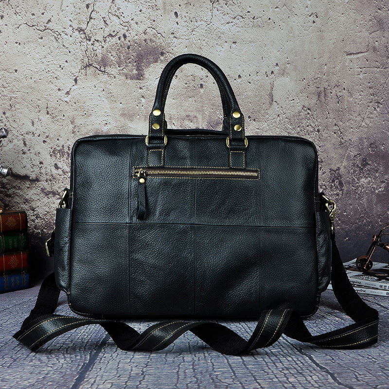 Black leather bag with gold zippers on a textured surface