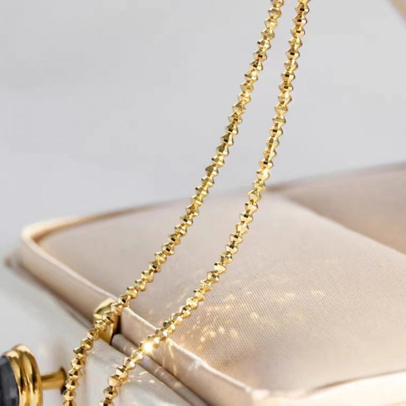 Gold necklace draped over a white handbag on a light gray background