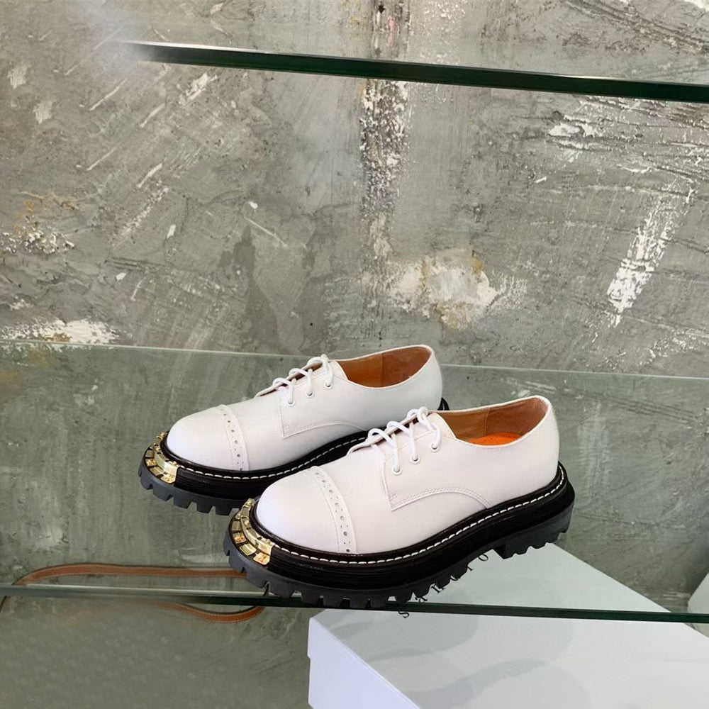 White shoes with black soles on a glass surface