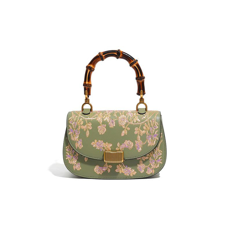 Green floral handbag with bamboo handle on a white background