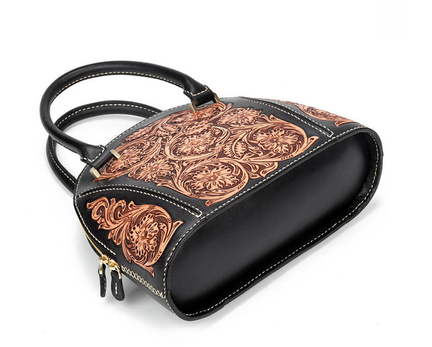 Black handbag with intricate copper embossed patterns on a white background