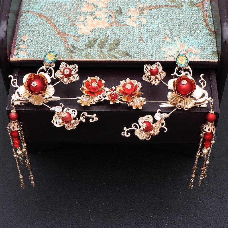 Decorative headpiece with red and gold flowers on a black stand with a floral-patterned box in the background.