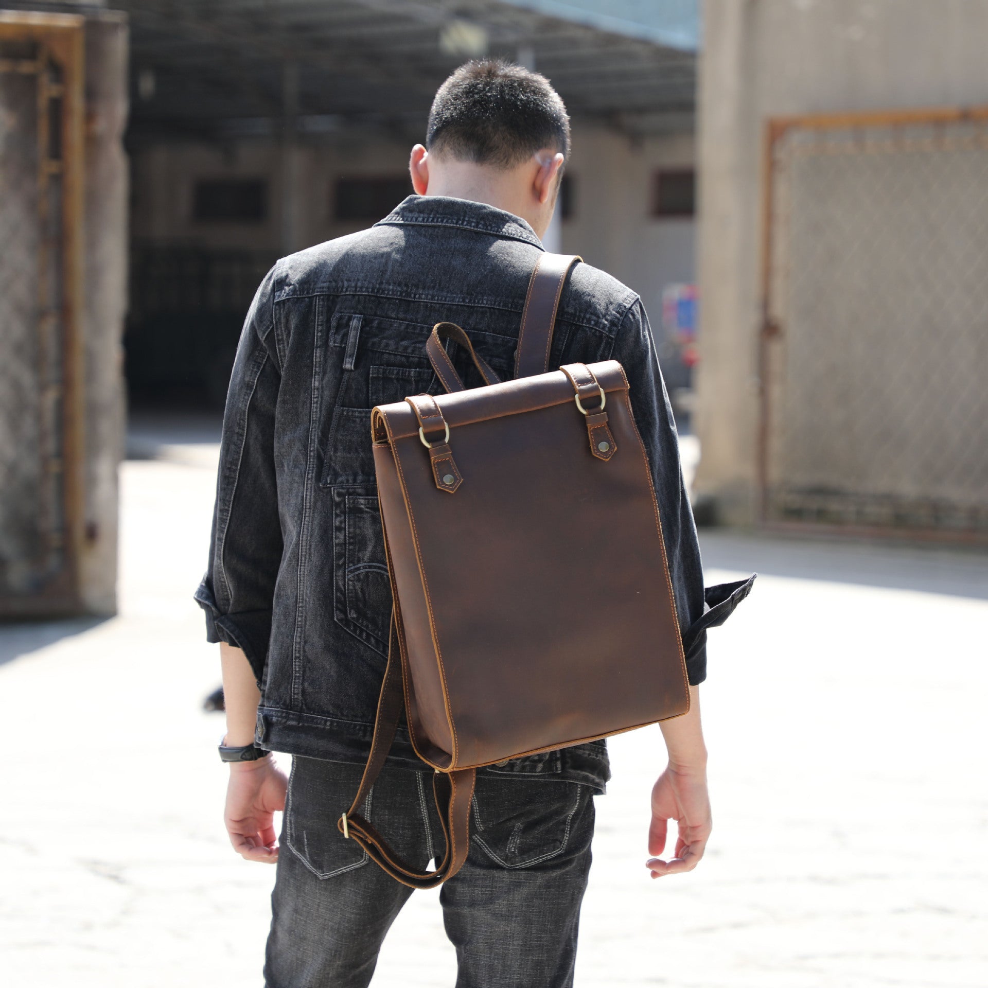 Person wearing a brown leather backpack outdoors