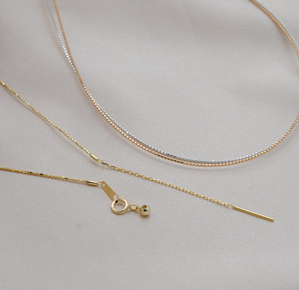 Two gold necklaces on a light gray background