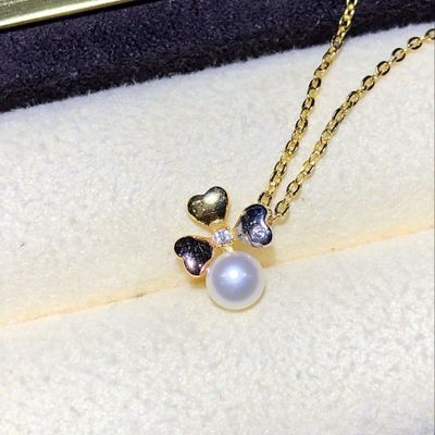 Gold necklace with a heart-shaped pendant and pearl on a white surface