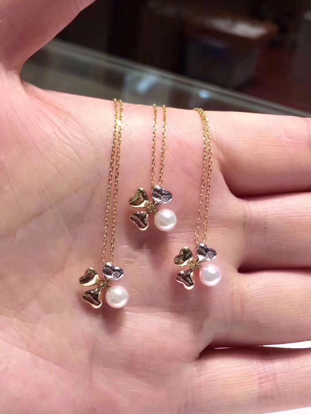 Gold necklaces with heart and pearl pendants on a hand