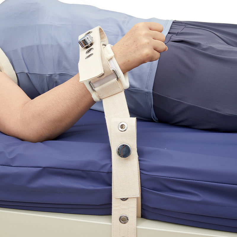 Person wearing a medical restraint strap on a blue bed
