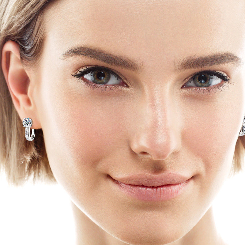 Close-up of a woman wearing silver hoop earrings with a plain background