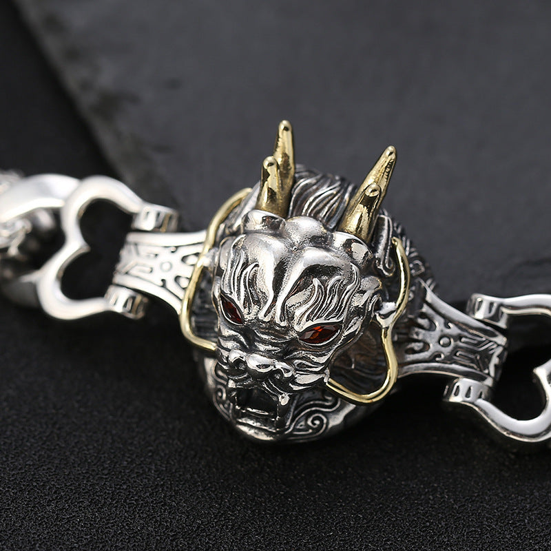 Silver and gold dragon head keychain on a dark background