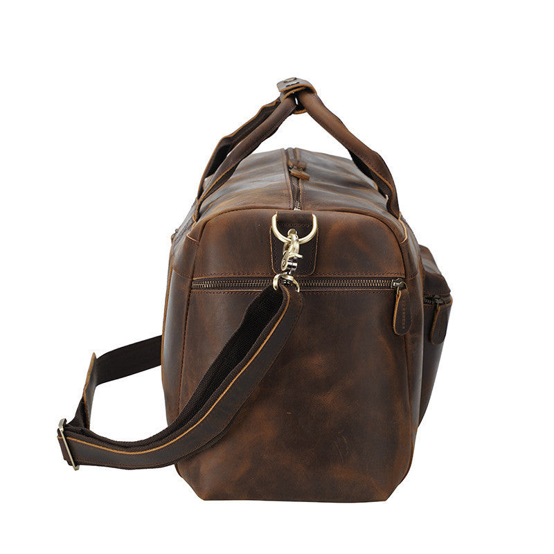 Brown leather duffel bag with a shoulder strap on a white background