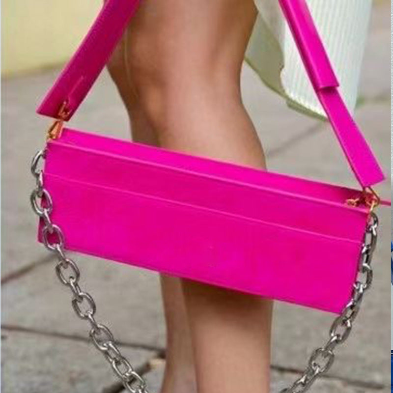 Hot pink handbag with a chain strap held by a person.