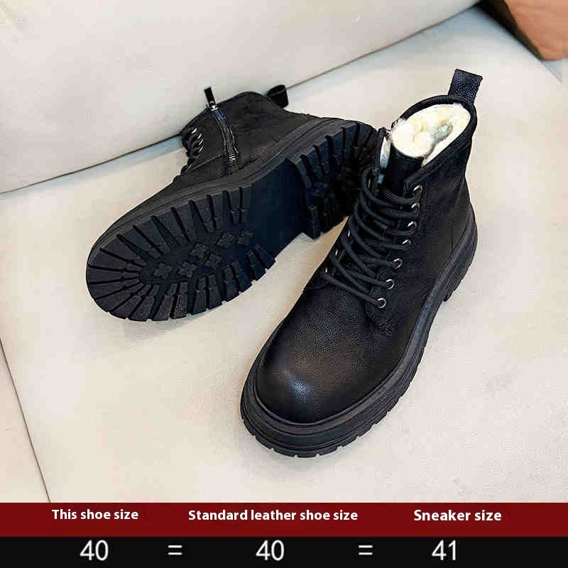 Black boots with white fur lining on a light gray surface