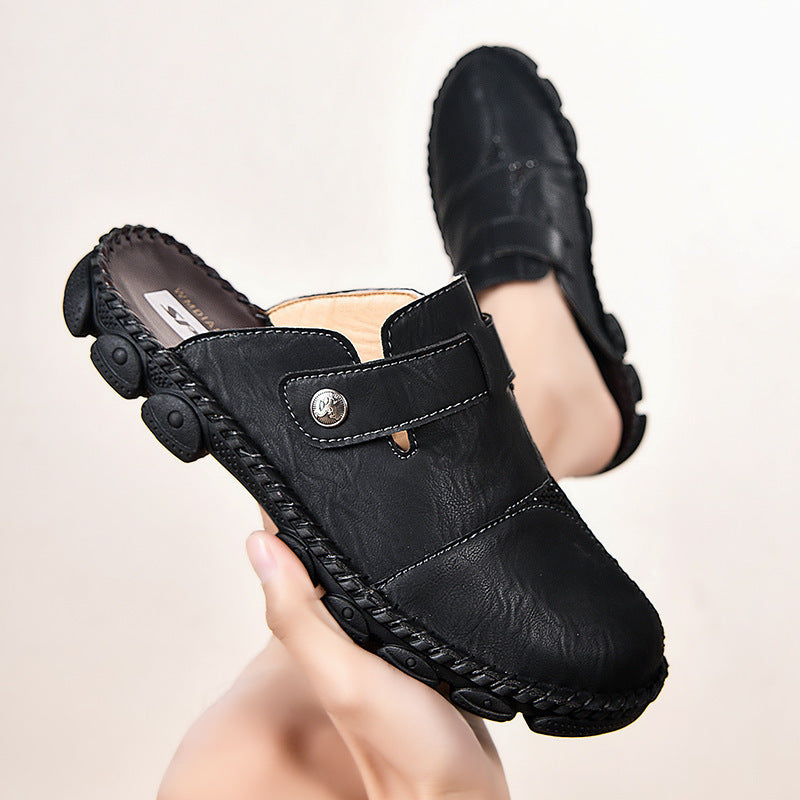 Black leather clogs held by a hand against a light background