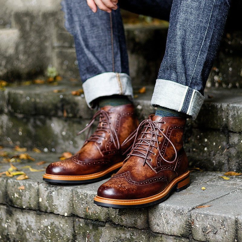 Brown leather boots worn with rolled-up jeans on stone steps.
