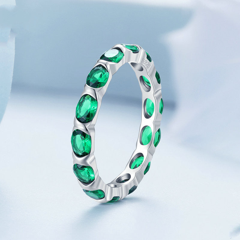 Silver ring with green gemstones on a light blue background