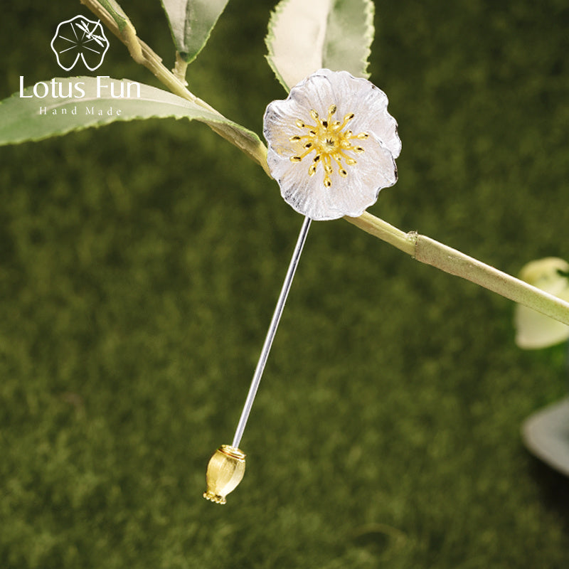 Floral brooch with gold accent on a green leafy background, featuring the Lotus Fun brand.