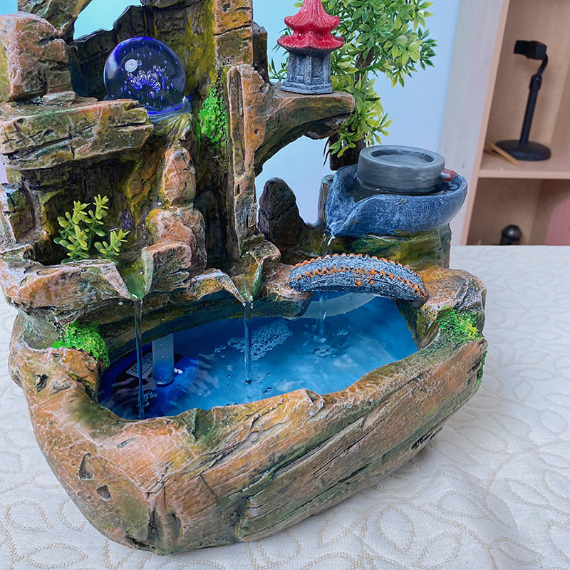 Decorative water fountain with rocks and blue water on a table.