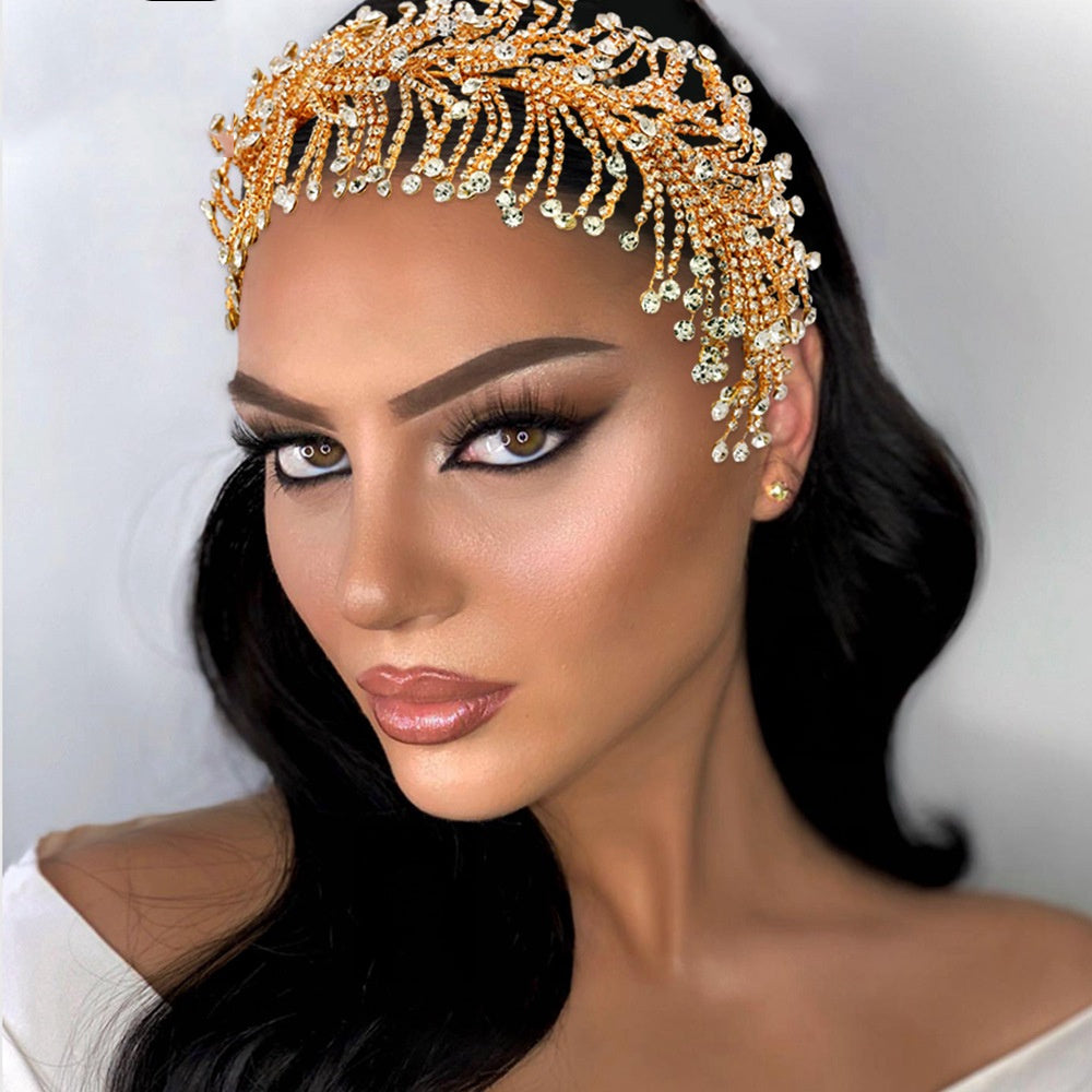 Woman wearing a gold headpiece with intricate designs on a plain background