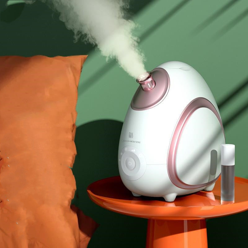 White and pink humidifier emitting mist on a green background