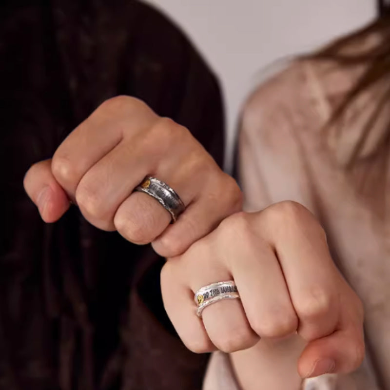 Two people holding hands with silver rings on a neutral background