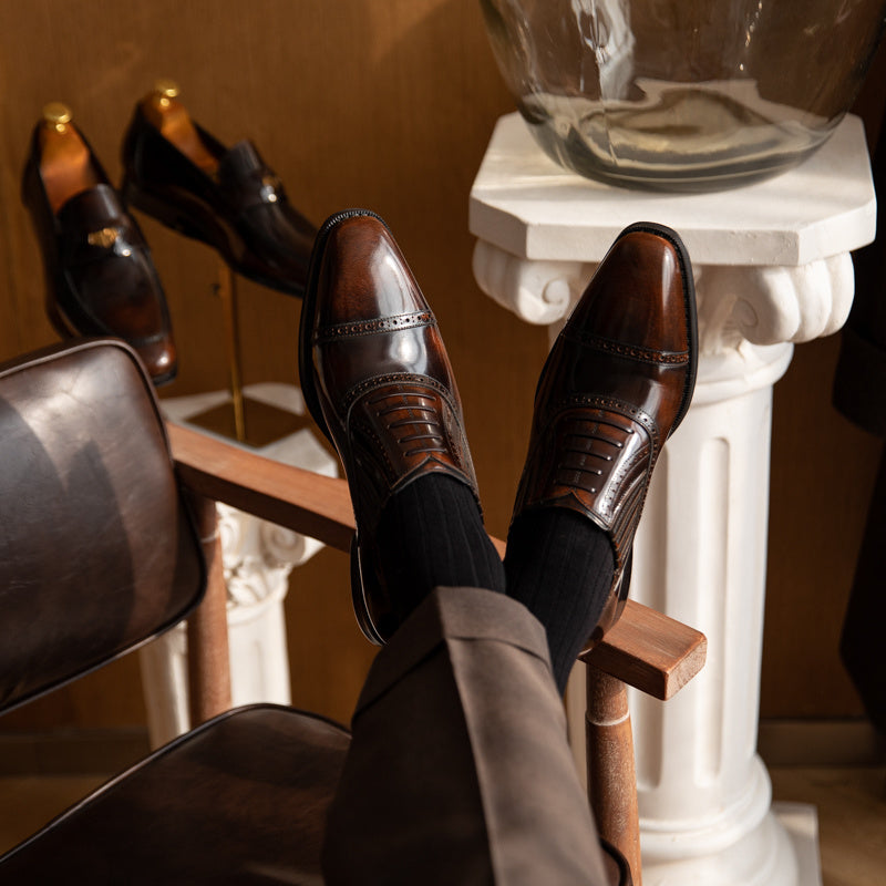 Brown leather shoes on a wooden stool with a decorative background