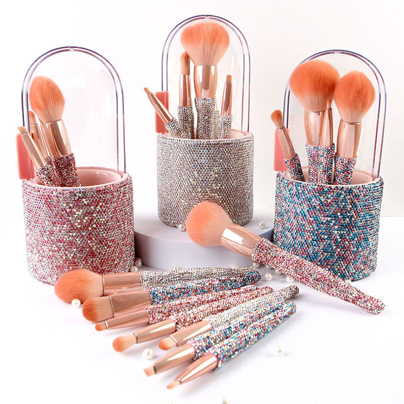 Makeup brushes in decorative holders on a white background