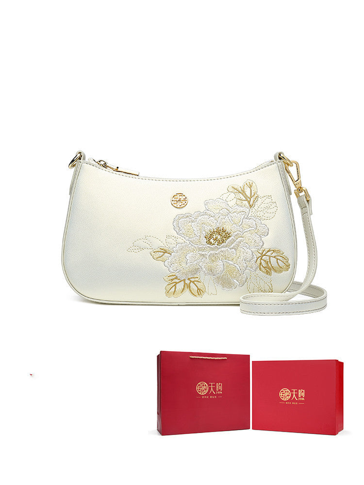 White handbag with floral embroidery and matching red box on a white background