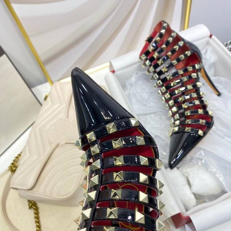 Black high-heeled shoes with gold and red studded design on a white background