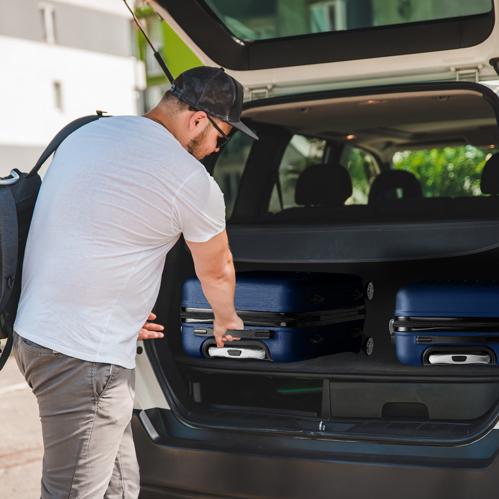 Man loading suitcases into the trunk of a car