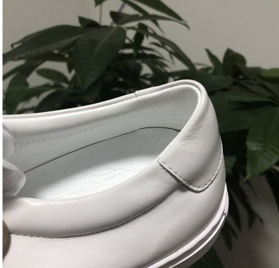 White shoe with a bow on a blurred plant background