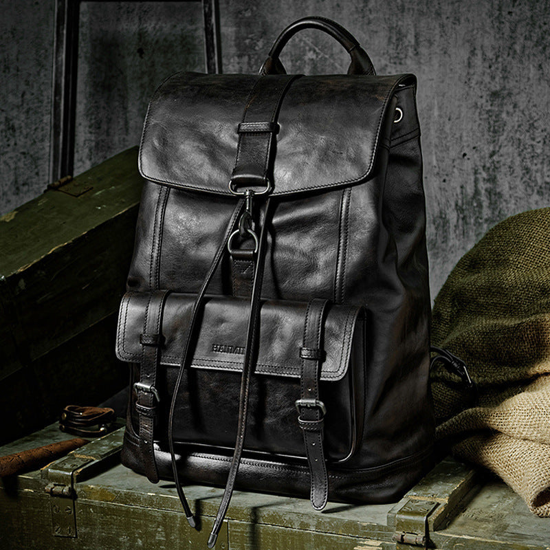 Black leather backpack on a rustic wooden surface with a textured gray background